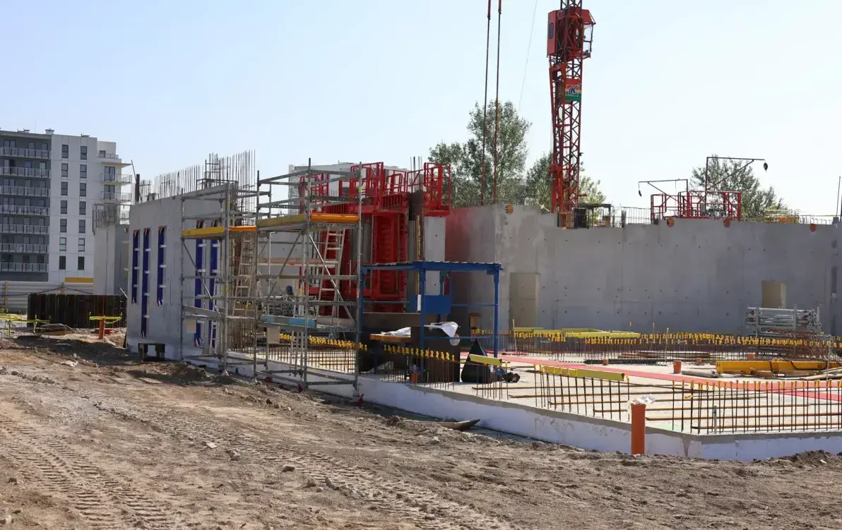 Zdjęcie przedstawia budowę - widoczne fundamenty i maszyny budowlane