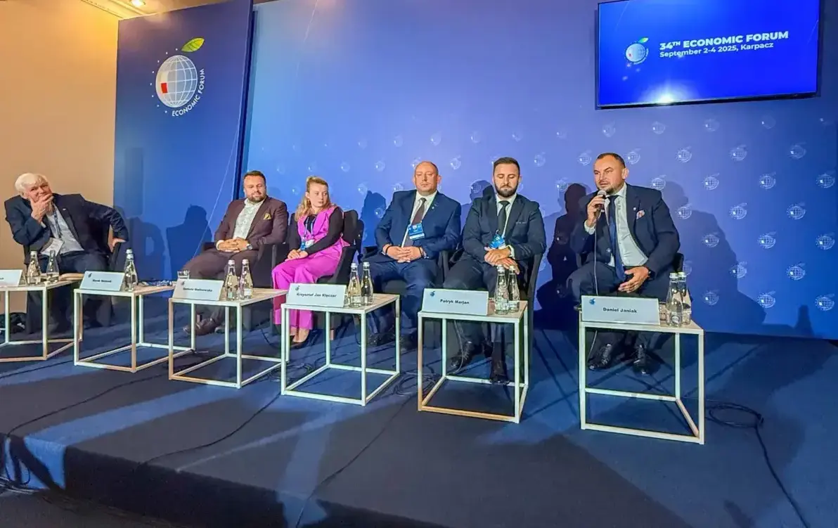 Zdjęcie przedstawia grupę osób siedzących na scenie