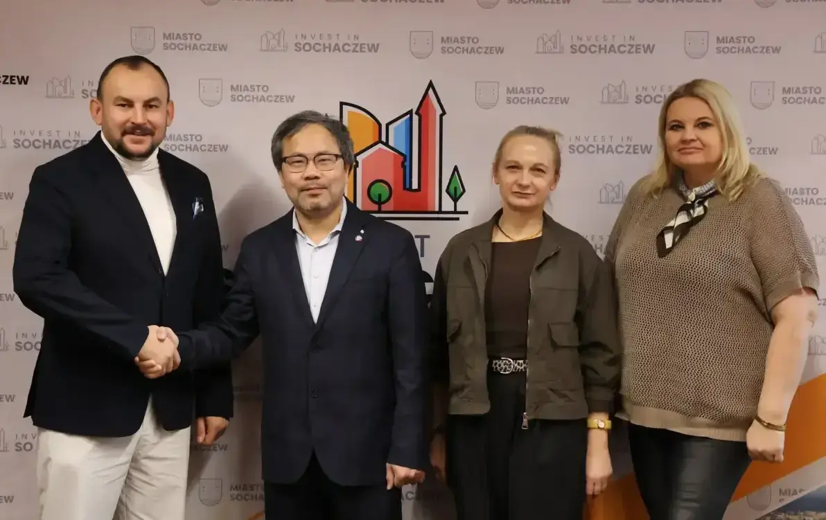 Zdjęcie przedstawia cztery osoby stojąće na tle ścianki z napisem Invest in Sochaczew