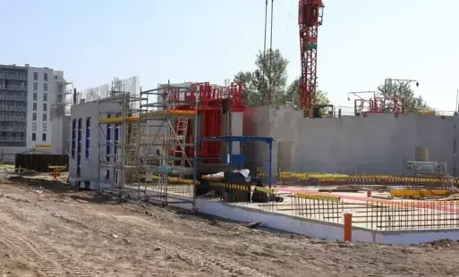 Zdjęcie przedstawia budowę - widoczne fundamenty i maszyny budowlane
