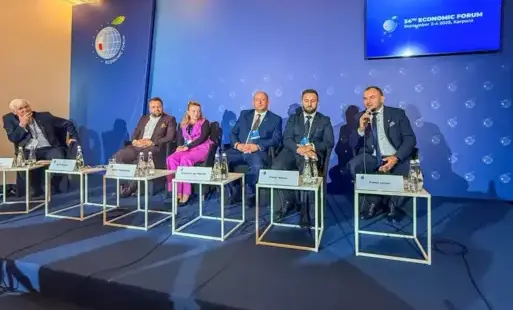 Zdjęcie przedstawia grupę osób siedzących na scenie